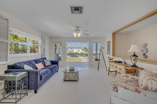 living area featuring a healthy amount of sunlight, visible vents, ceiling fan, and wood finished floors