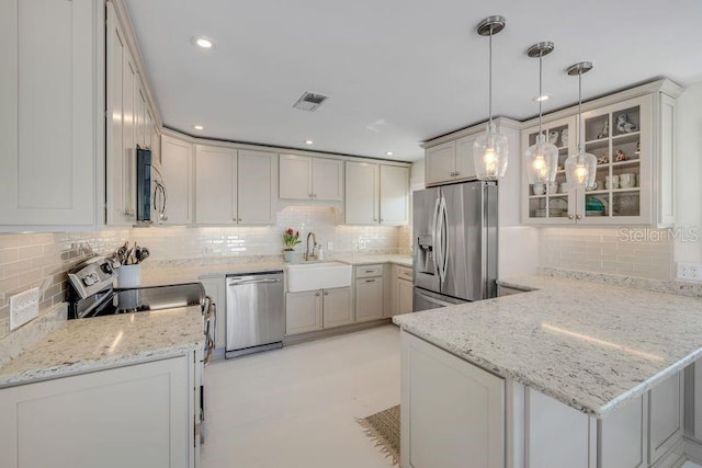 kitchen with light stone counters, a peninsula, a sink, visible vents, and appliances with stainless steel finishes