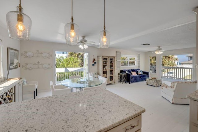 kitchen featuring a wealth of natural light, open floor plan, decorative light fixtures, and light stone countertops