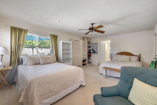 bedroom featuring a textured ceiling, ceiling fan, and light colored carpet