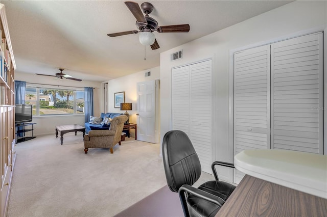 carpeted office space featuring a ceiling fan, visible vents, and a textured ceiling