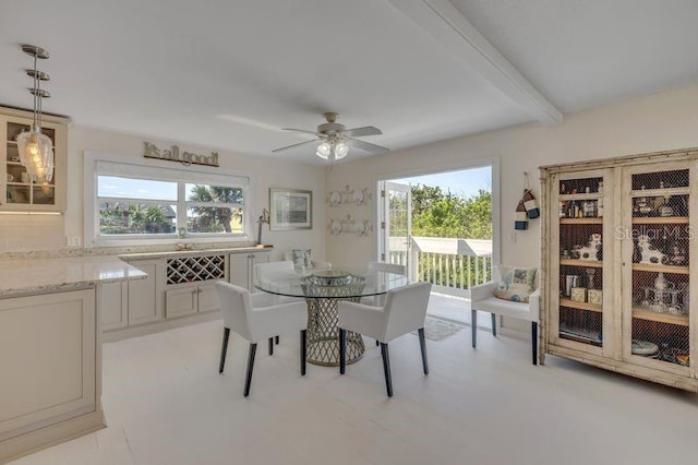 dining area featuring a healthy amount of sunlight, ceiling fan, and beam ceiling