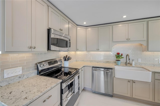 kitchen featuring light stone counters, recessed lighting, backsplash, appliances with stainless steel finishes, and a sink