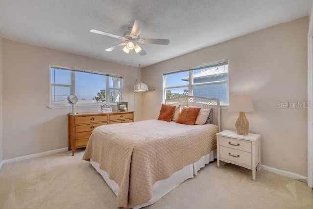 bedroom with ceiling fan, baseboards, and light colored carpet