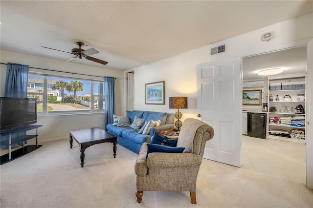 living room featuring a textured ceiling, visible vents, a ceiling fan, and light colored carpet