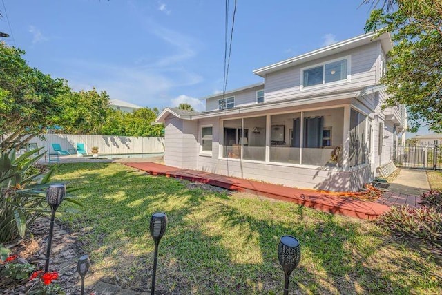 back of house with a sunroom, a fenced backyard, and a lawn