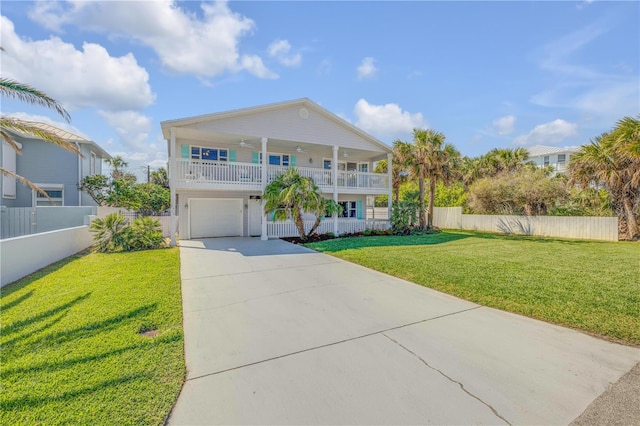 raised beach house with a garage, a front yard, concrete driveway, and fence