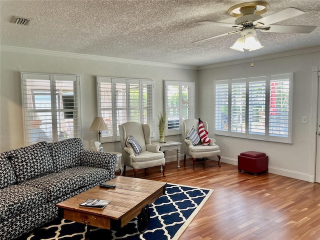 living room featuring a ceiling fan, wood finished floors, visible vents, and crown molding