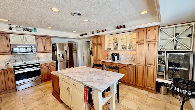 kitchen featuring stainless steel appliances, visible vents, a center island, brown cabinetry, and glass insert cabinets