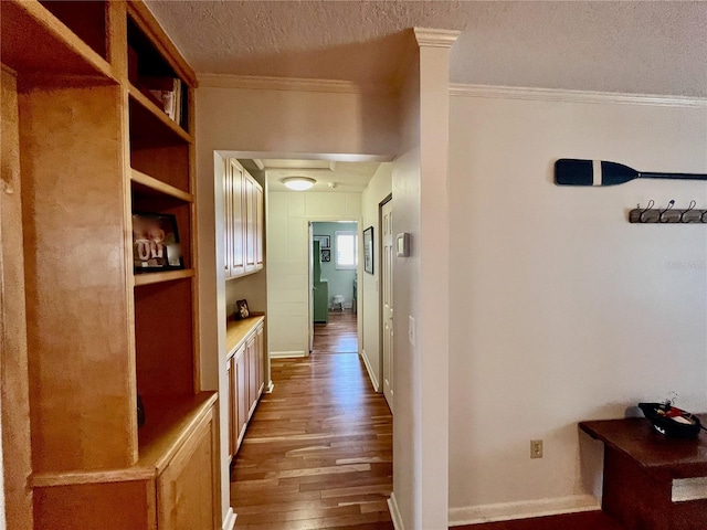 hall featuring ornamental molding, a textured ceiling, baseboards, and wood finished floors