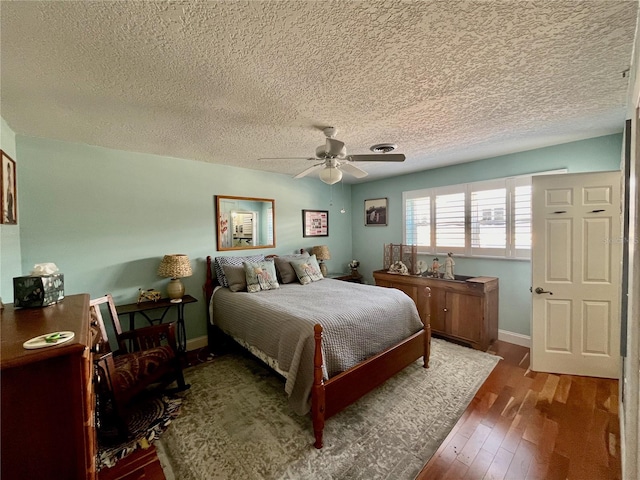 bedroom featuring ceiling fan, hardwood / wood-style floors, a textured ceiling, and baseboards