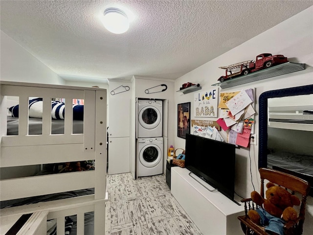 laundry area with light wood-style floors, stacked washer and clothes dryer, a textured ceiling, and laundry area