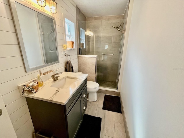 bathroom featuring a stall shower, vanity, toilet, and wood finished floors