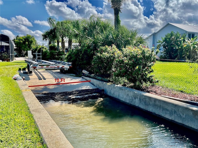 exterior space with a lawn, a water view, and fence