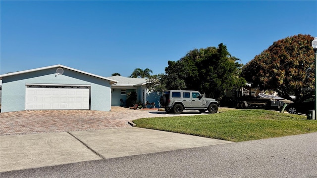 ranch-style home featuring a front lawn, decorative driveway, an attached garage, and stucco siding