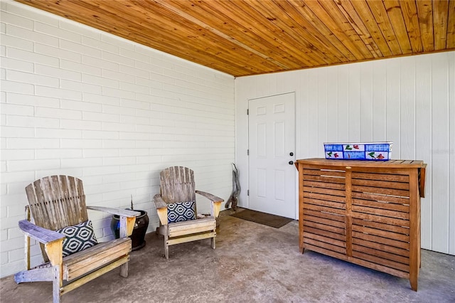 living area featuring wooden ceiling and brick wall