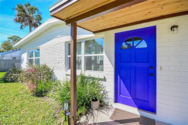 property entrance featuring fence and brick siding