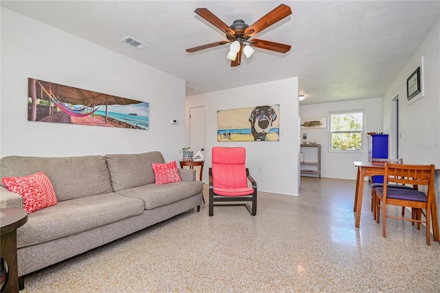 living room with ceiling fan, visible vents, and speckled floor