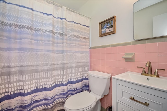 bathroom with tile walls, toilet, wainscoting, vanity, and a shower with curtain