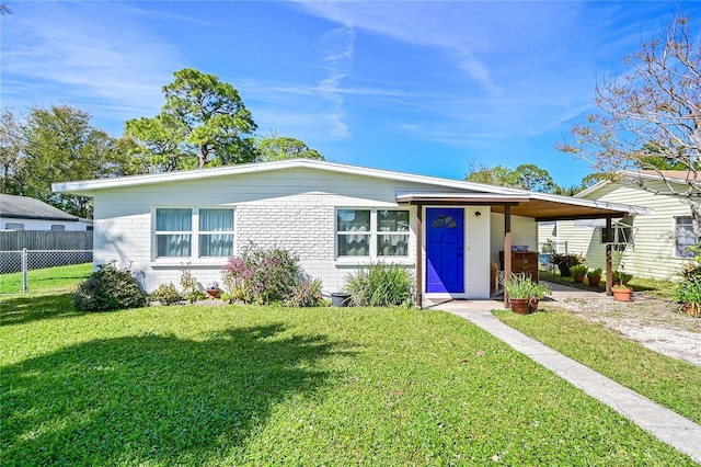 view of front of property featuring brick siding, fence, a carport, and a front yard