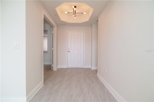 hallway with a raised ceiling and baseboards