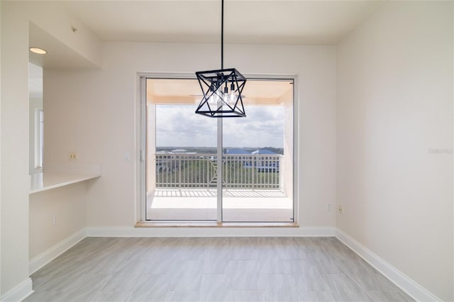 unfurnished dining area with a chandelier and baseboards