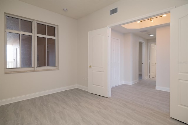 empty room featuring visible vents, light wood-style flooring, and baseboards