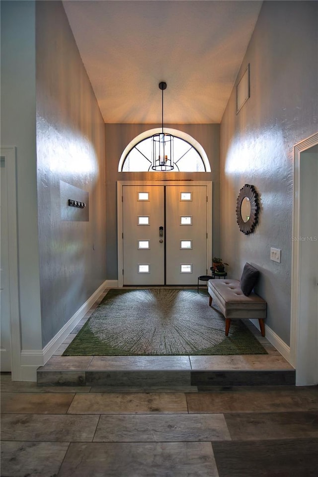 entryway with vaulted ceiling, wood finished floors, and baseboards