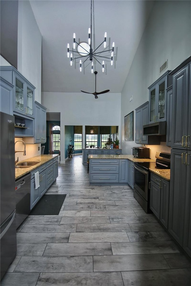 kitchen featuring visible vents, a peninsula, stainless steel appliances, wood finish floors, and a sink