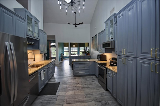 kitchen featuring wood finish floors, a sink, blue cabinetry, appliances with stainless steel finishes, and decorative backsplash