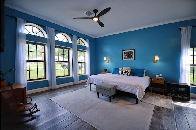 bedroom featuring ornamental molding, wood finished floors, visible vents, and baseboards