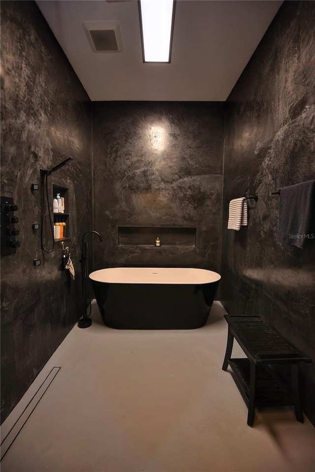 full bath with a freestanding tub, finished concrete floors, and visible vents