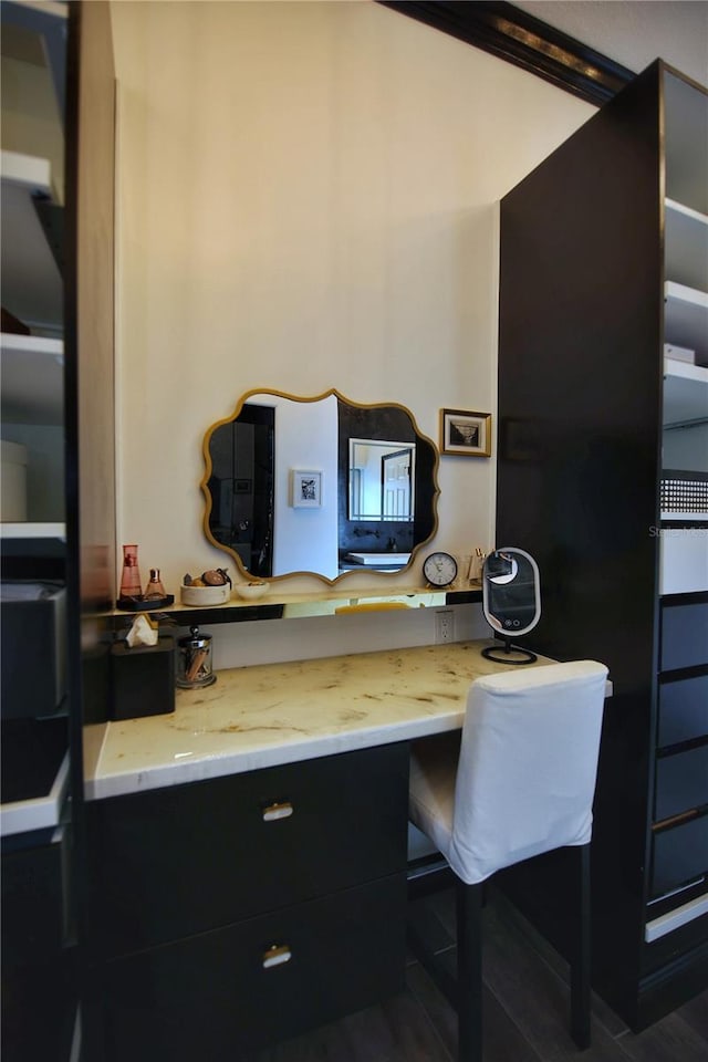 kitchen with light stone counters, dark cabinetry, and built in study area