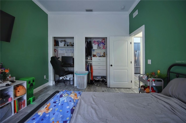 bedroom with crown molding, visible vents, wood finished floors, and freestanding refrigerator