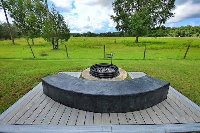 wooden deck with a rural view, an outdoor fire pit, and a lawn