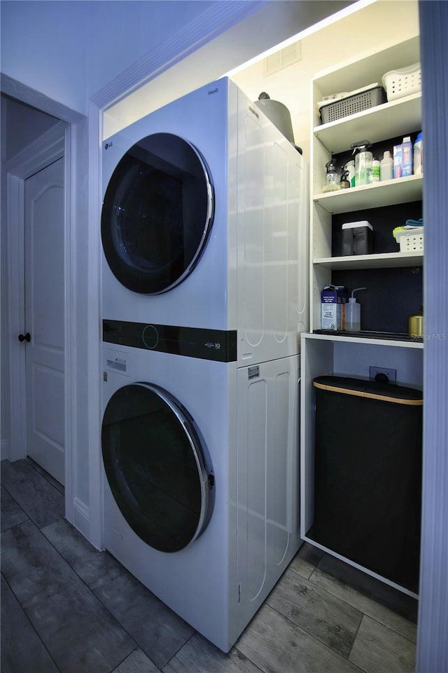 laundry room featuring stacked washing maching and dryer, laundry area, and wood finished floors