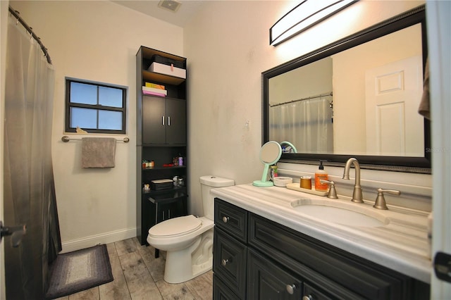 bathroom with visible vents, toilet, vanity, wood finished floors, and baseboards