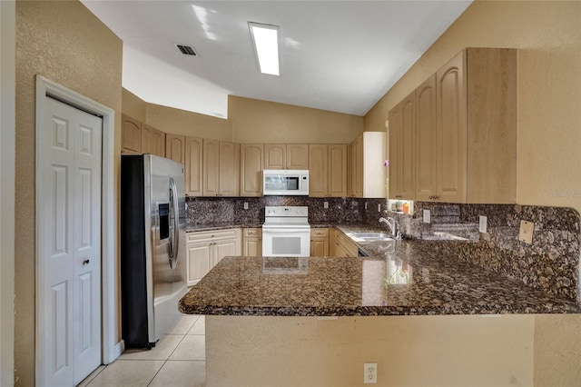 kitchen with light brown cabinets, a peninsula, white appliances, a sink, and tasteful backsplash