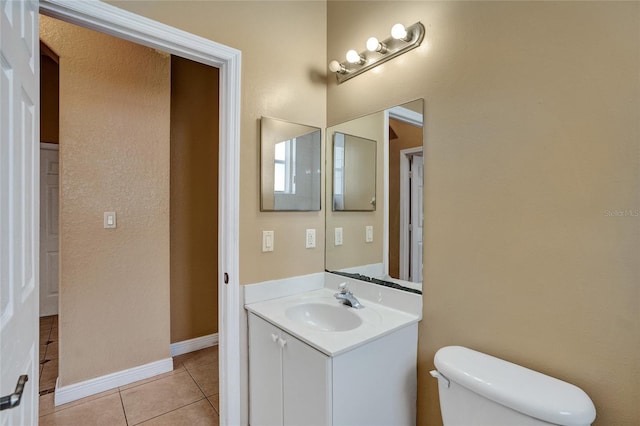 bathroom with toilet, vanity, baseboards, and tile patterned floors