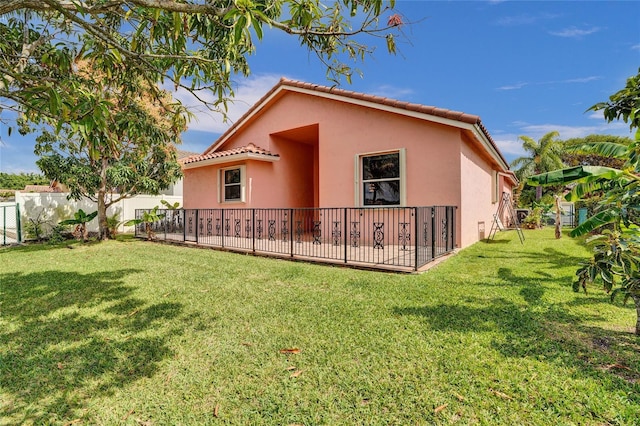 back of property with fence private yard, a yard, and stucco siding