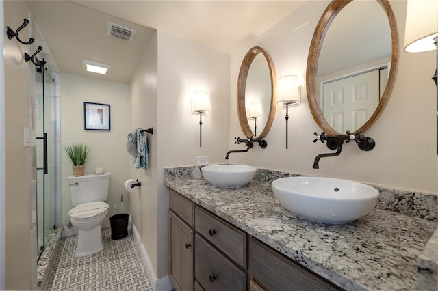 bathroom featuring toilet, double vanity, visible vents, and a sink