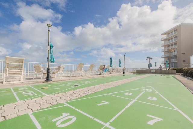 view of property's community with fence and shuffleboard