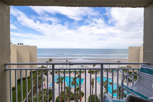 balcony with a water view and a view of the beach