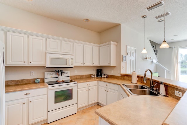 kitchen featuring white appliances, a peninsula, light countertops, pendant lighting, and a sink