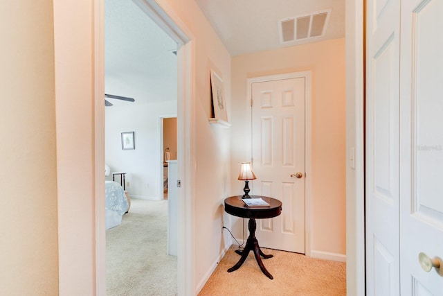 hall with carpet flooring, visible vents, and baseboards