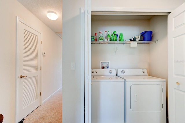 clothes washing area featuring carpet, washing machine and dryer, a textured ceiling, laundry area, and baseboards