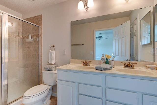 bathroom featuring double vanity, a stall shower, a sink, and toilet