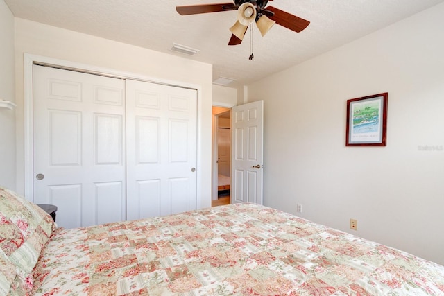 bedroom featuring ceiling fan, a textured ceiling, visible vents, and a closet