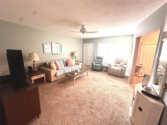 living area with ceiling fan, a textured ceiling, and carpet