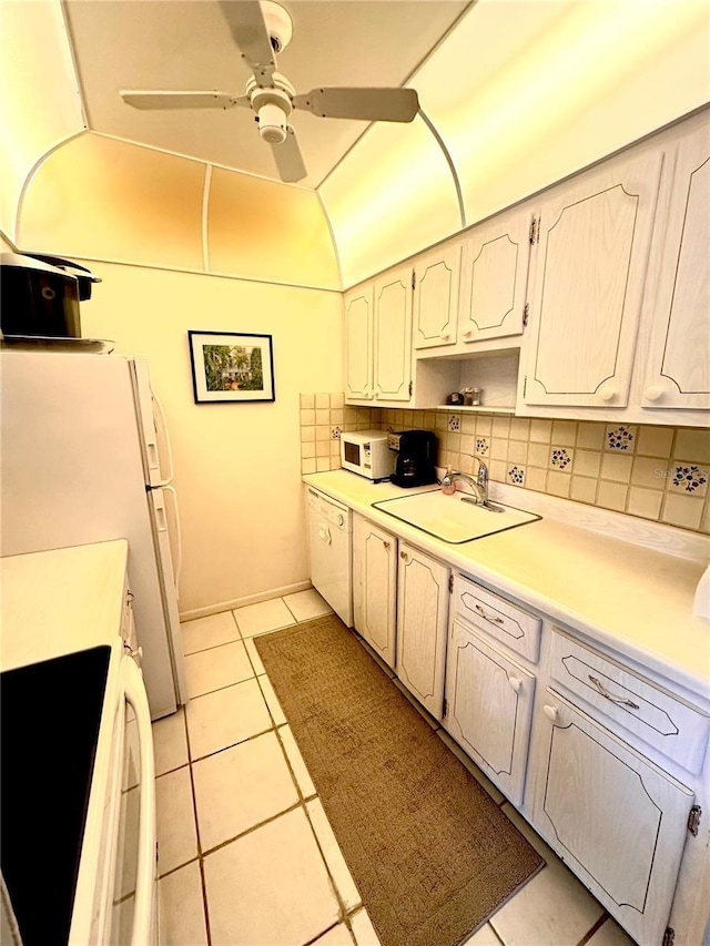 kitchen featuring white appliances, light tile patterned floors, decorative backsplash, light countertops, and a sink